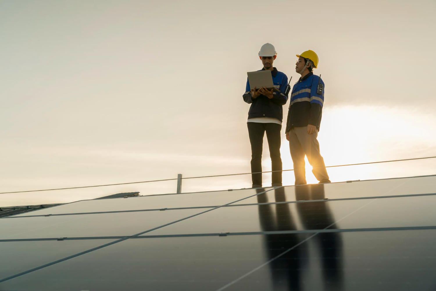 Techniciens inspectant des panneaux solaires avec ordinateur pour Photon Solaris sur un toit à Fleurance au coucher du soleil