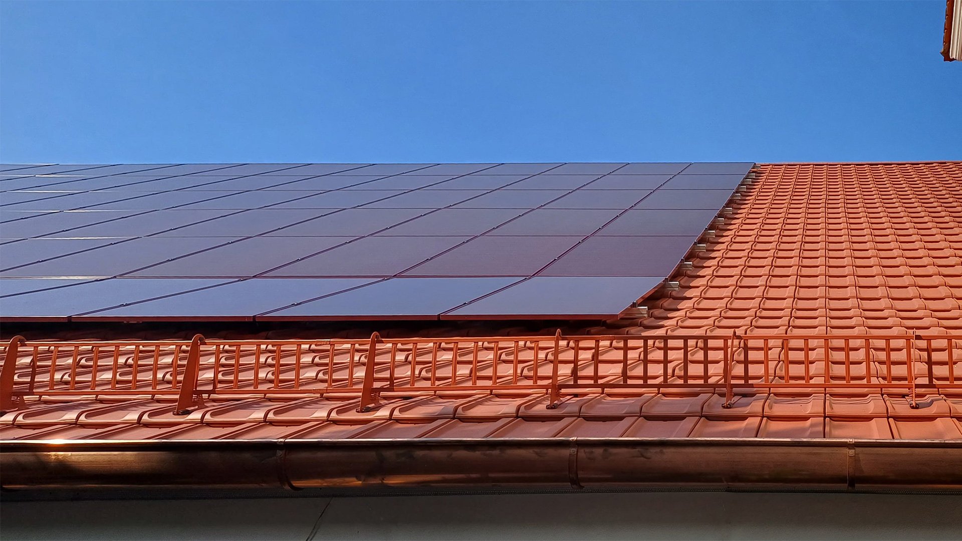 Panneaux solaires sur toit en tuiles orangées installés par Photon Solaris à Fleurance sous ciel bleu